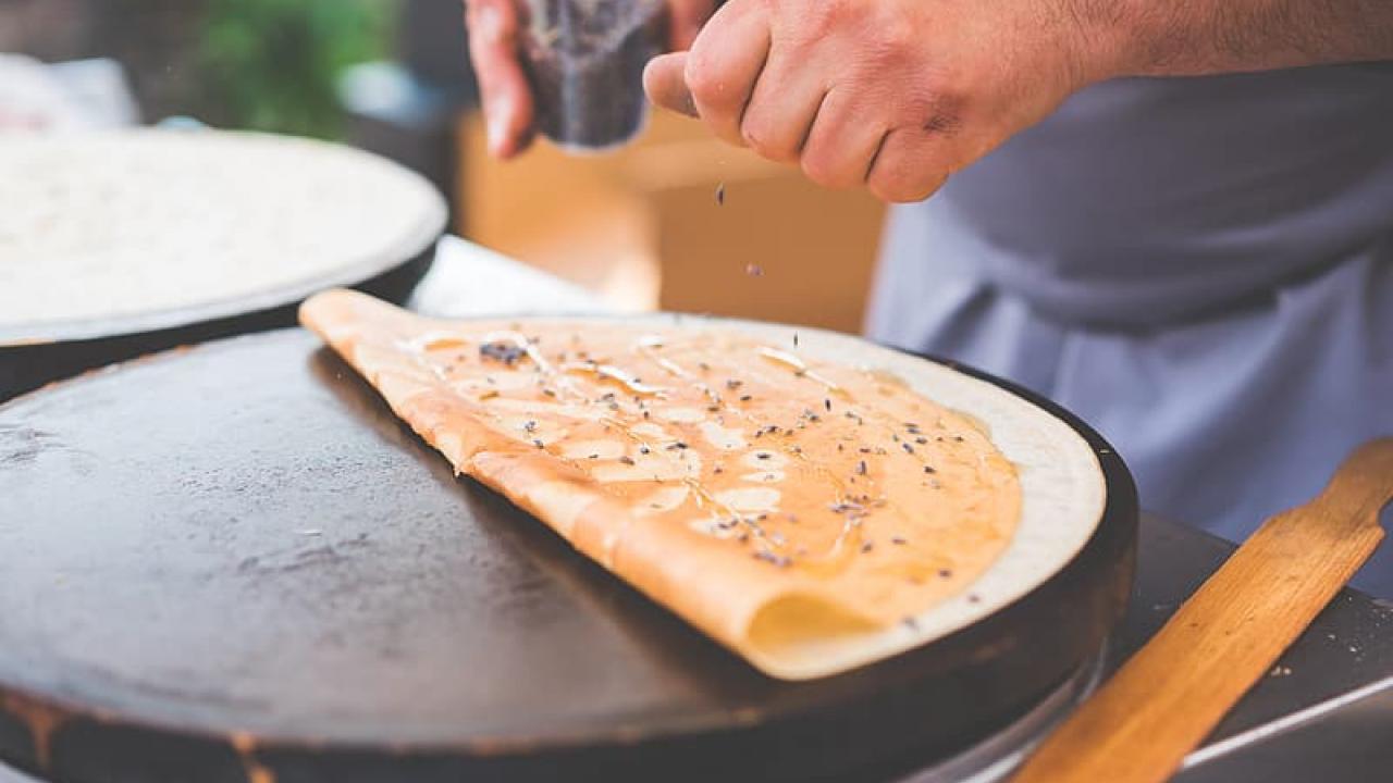 Picture of someones hands making crepes.