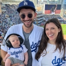 萨姆·弗莱舍（Sam Fleischer）和妻子和孩子站在道奇体育场（Dodgers stadium）。每个人都穿着白色和蓝色道奇队球衣。 