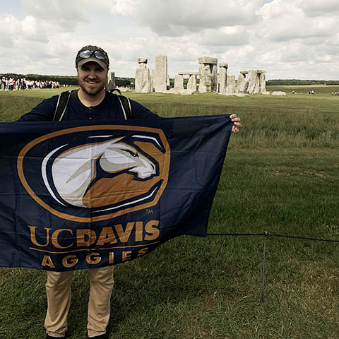 Person with UC Davis flag in front of Stonehenge