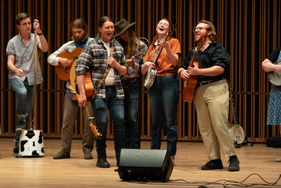 Group of people singing and holding instruments on a stage