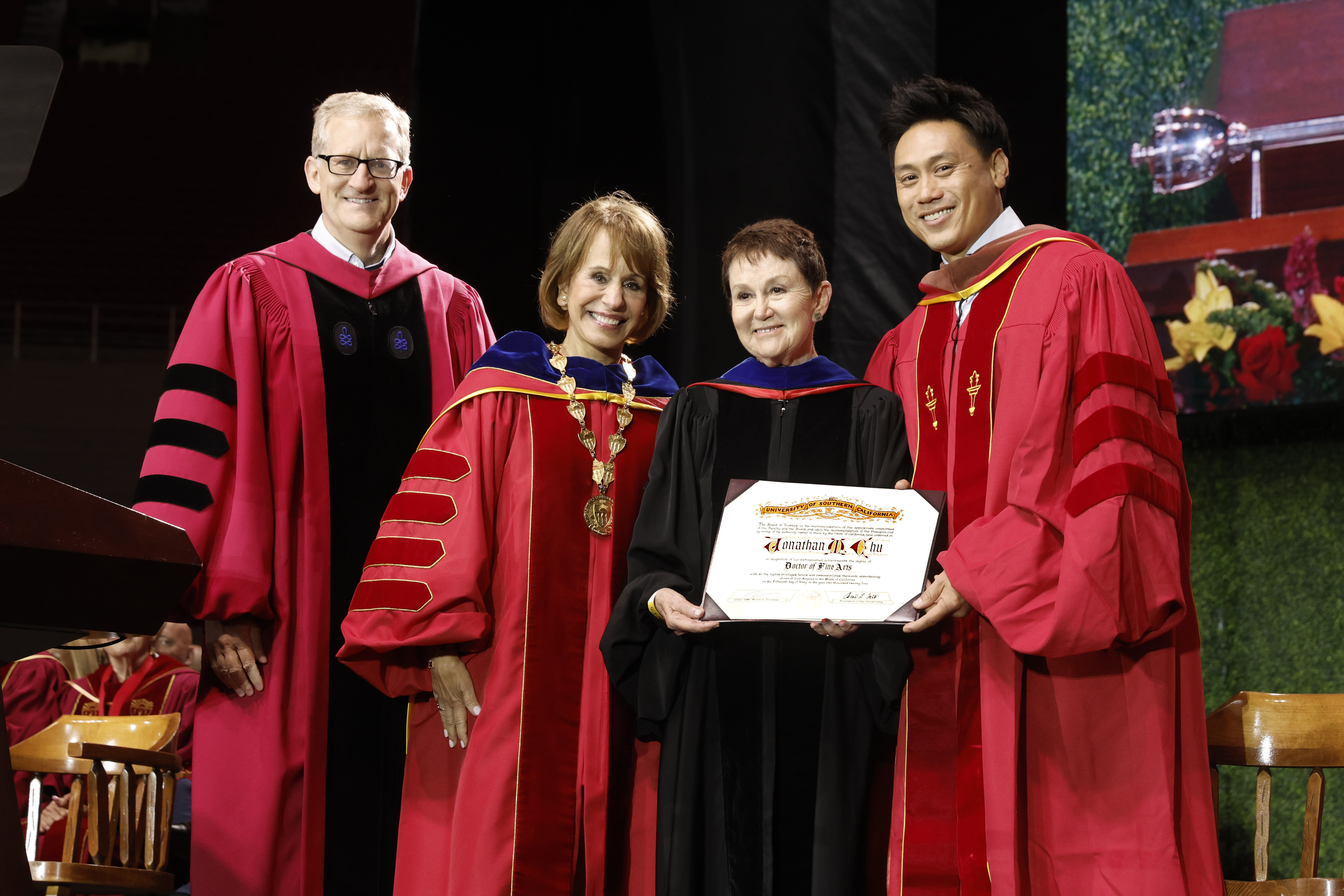 Carol Folt, second from left, presents an honorary degree to USC alum and award-winning filmmaker Jon Chu at 2025 commencement.