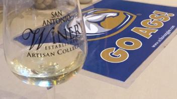 Empty wine glass and Go Ags! sign on a table 