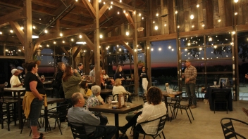 Man giving a talk about the estate and the wine in the center of the room among people sitting at tables