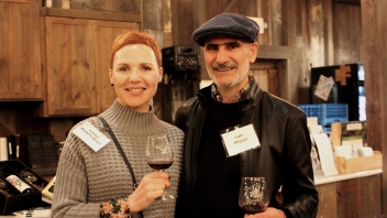 Couple smiling at the camera drinking wine. 