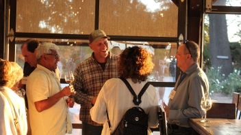 Man speaking to three people inside the Herringer estate as the sun begins to go down casting a golden light. 