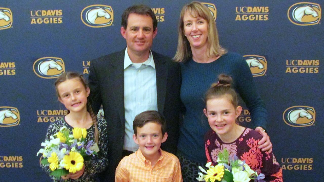 David Nix posing with his family in front of a UC Davis Aggies backdrop