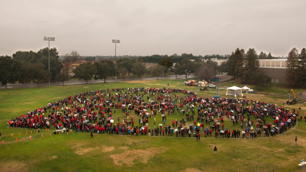 An aerial shot of a group of people forming a heart at Hutchison Field