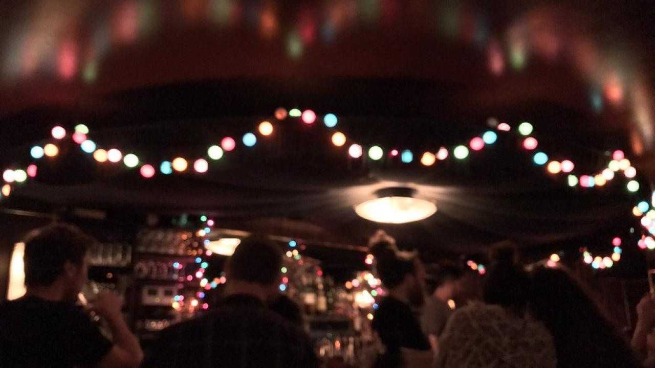 Blurry image of a bar with holiday lights hung from the ceiling.