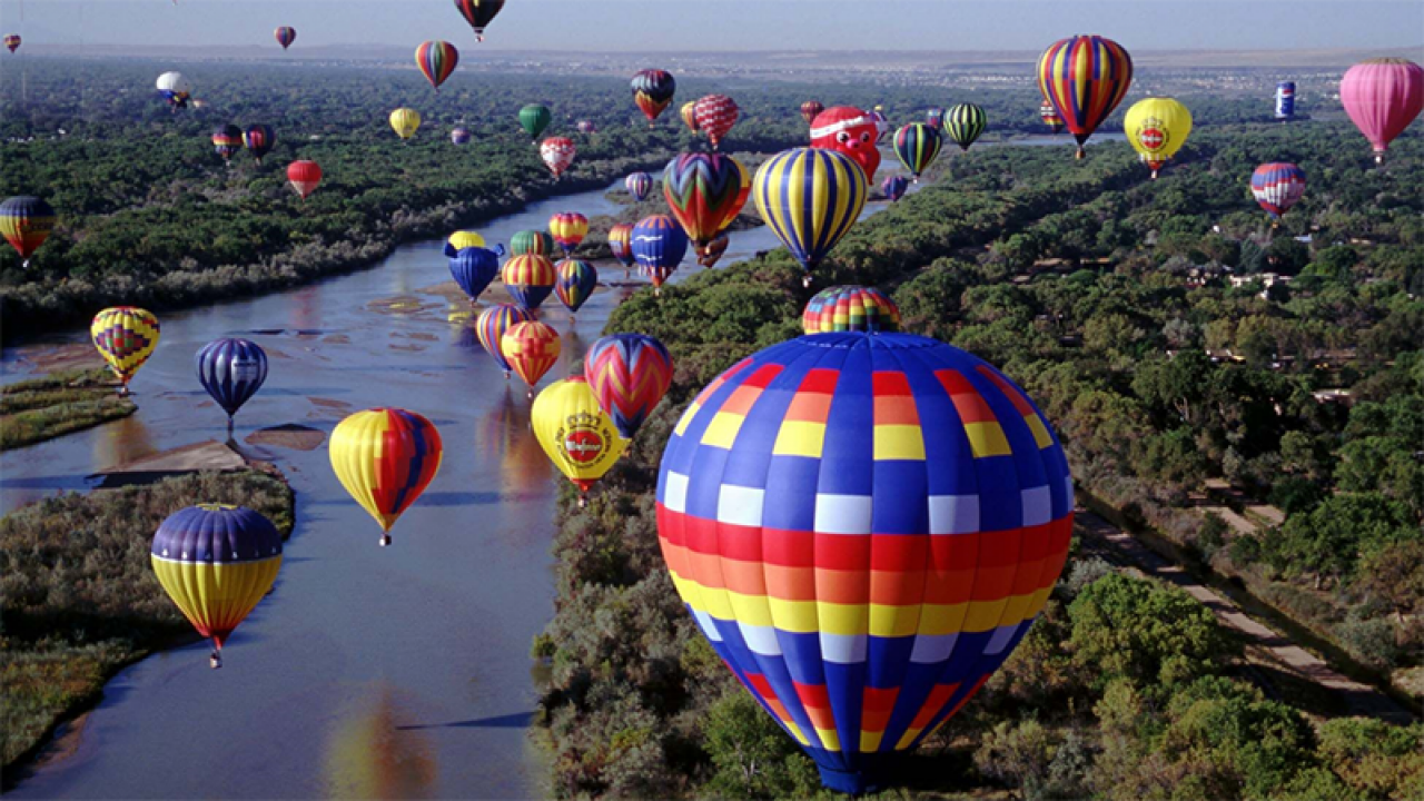 Several hot air balloons flying over water in Albuquerque.