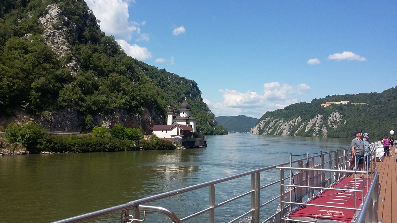 Taken from on board a ship, looking out into the iron gate gorge surrounded by mountains covered in lush greenery and sheer cliffs.