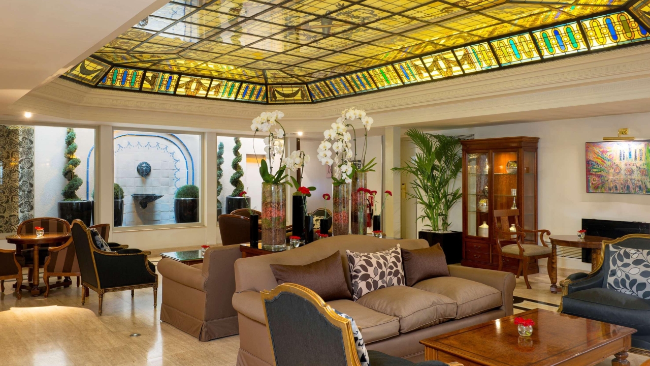 photo of hotel lobby with stained glass tiles towards the ceiling and seating in the middle of the image