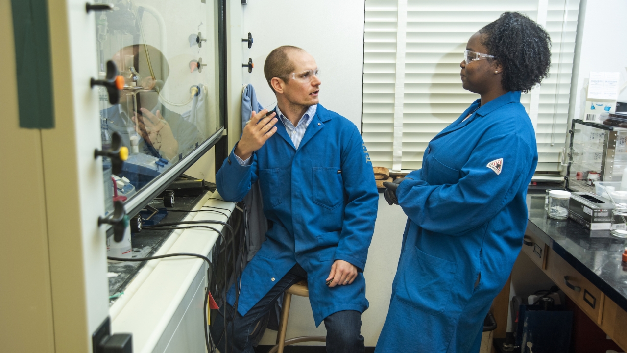Chancellor's Fellow and Professor David Olson in a lab room with another person.