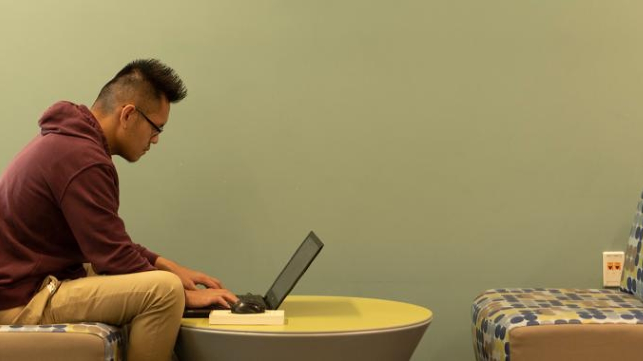A man sits at the MU and uses his laptop