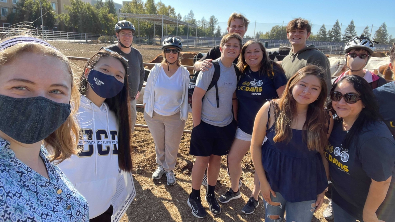 A group of students and parents pose for a group photo in front of the UC Davis Dairy.