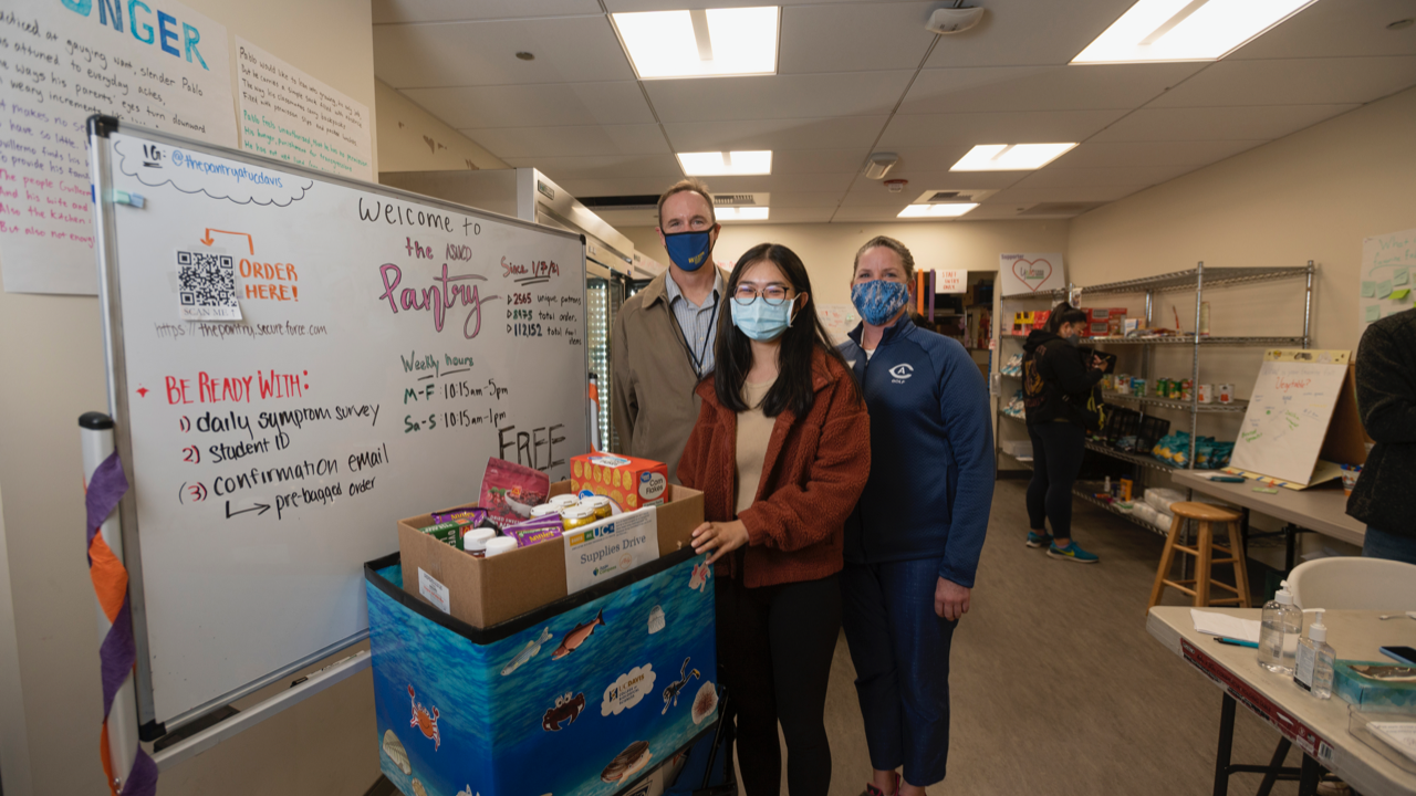 student wearing a mask standing next to a box of food in the UC Davis pantry