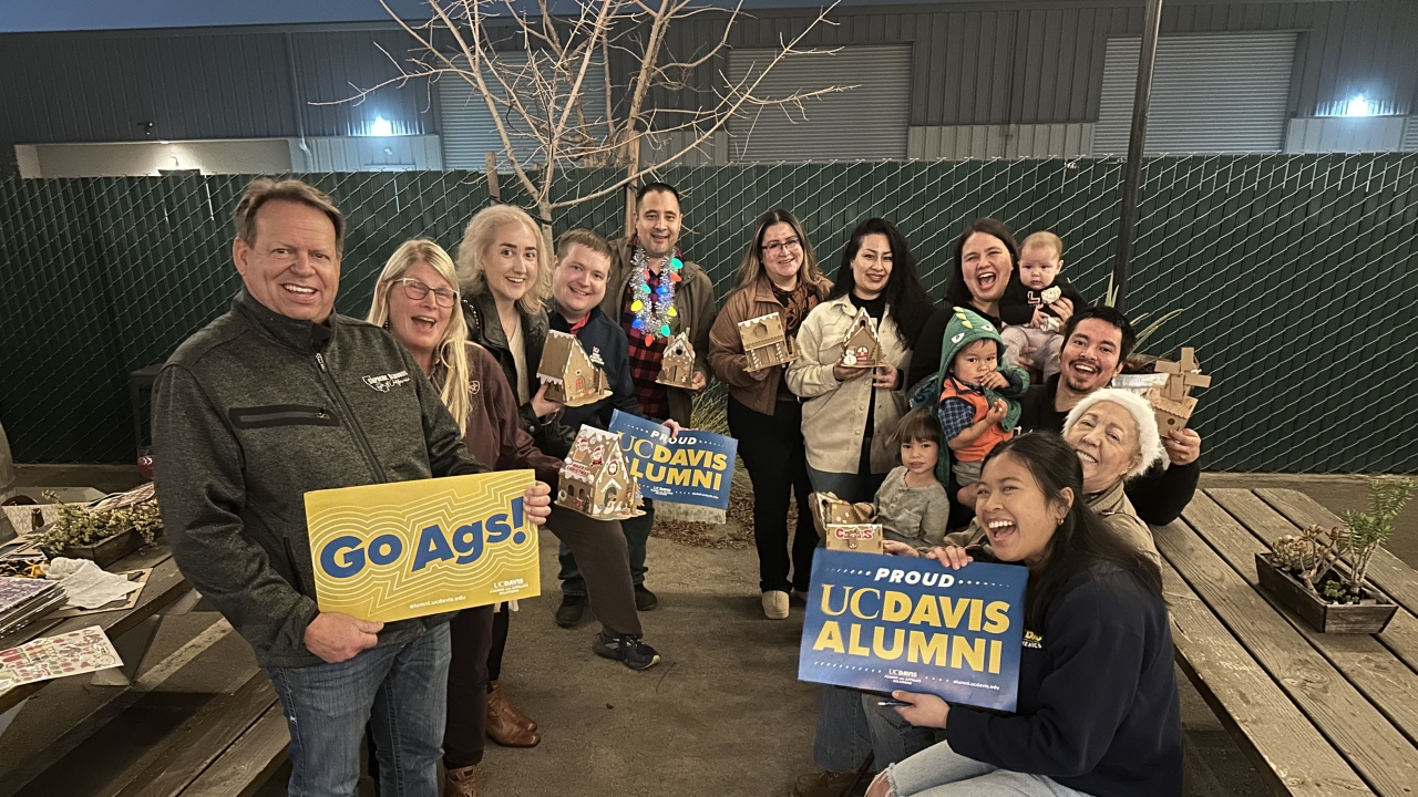 Fresno alumni holding signs saying "Go Ags!" and "Proud UC Davis Alumni" as well as gingerbread houses