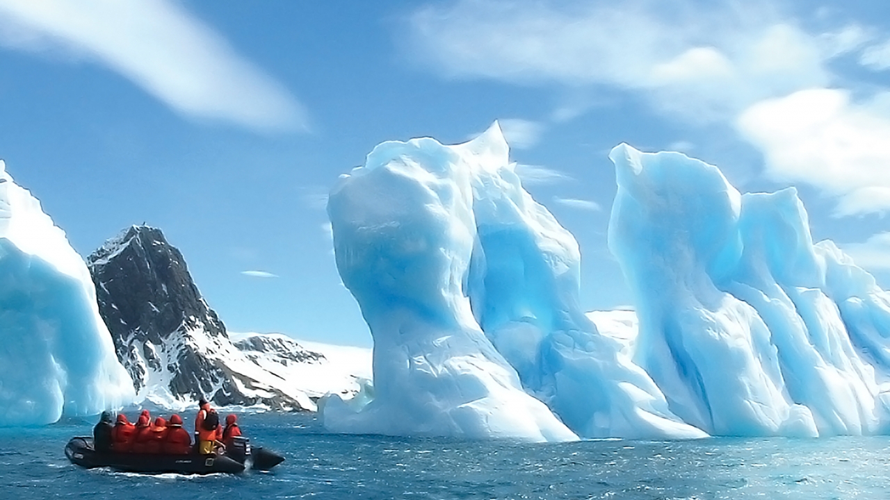 Aggie Travel members aboard a Zodiac craft observe the floating ice sculptures on the water's surface.