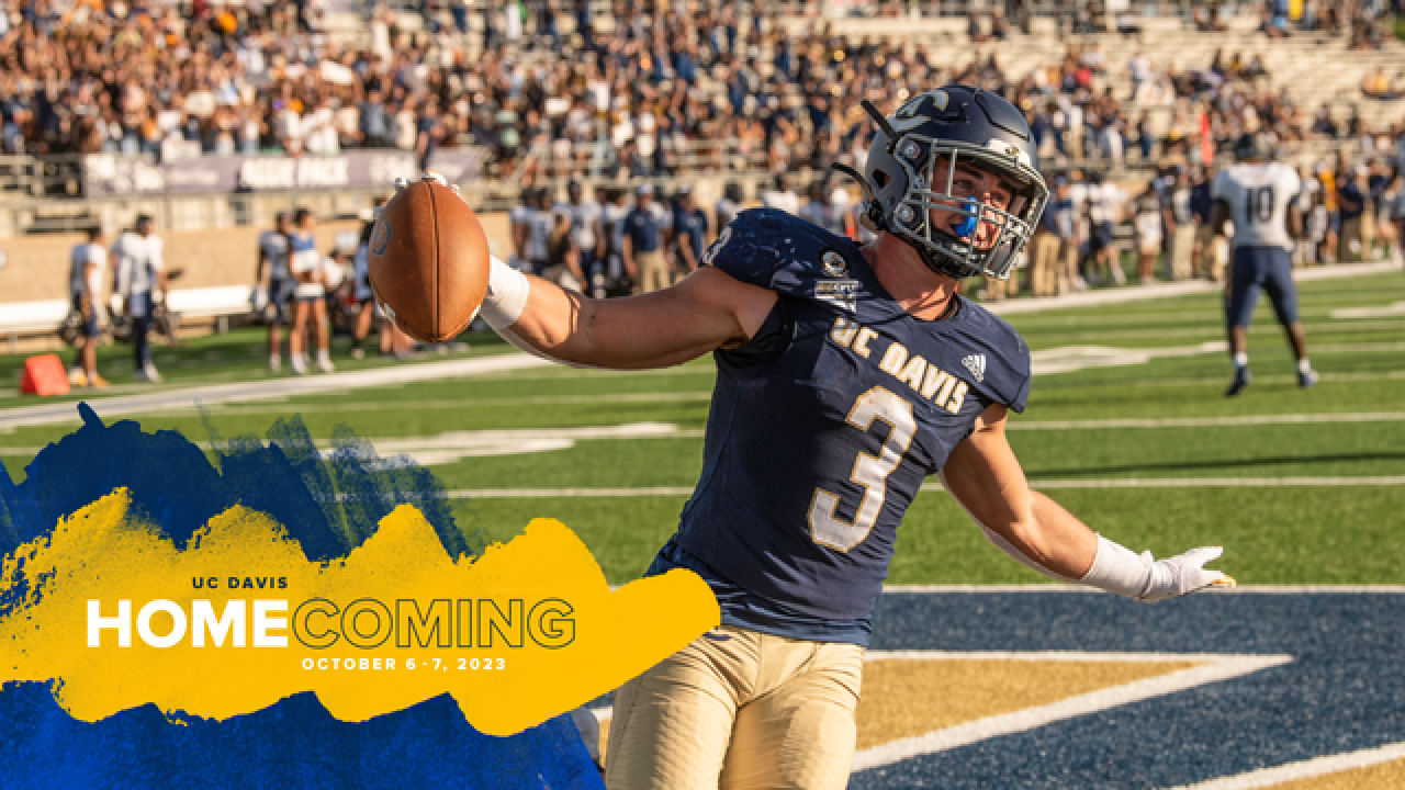 UC Davis football player holding a football with their arms open and a gold Homecoming banner with the date of homecoming.