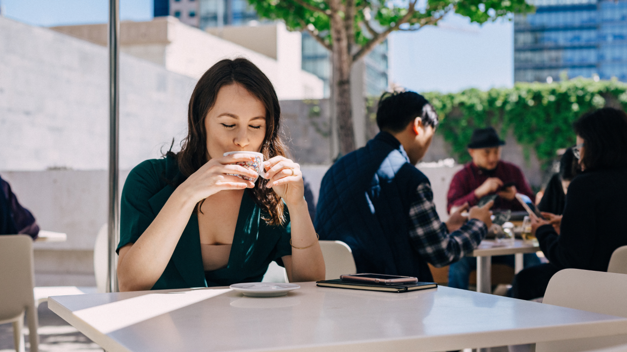 Brandy drinking cup of coffee at table outdoors