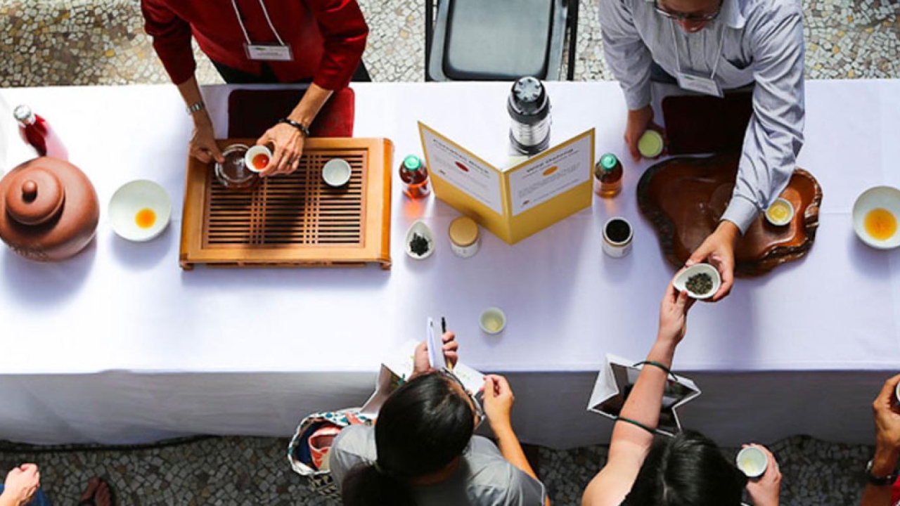 Photo of a table with people reaching across and tea pots