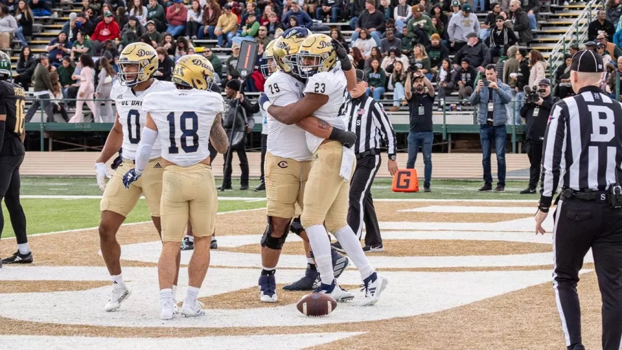 UCD football players celebrating touchdown in the end zone