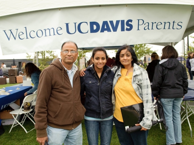 Image of three people in front of a Welcome UC Davis Parents sign