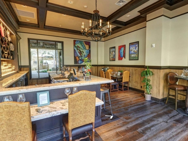 Cozy upscale dining room with wooden beams, chandeliers, and colorful wall art