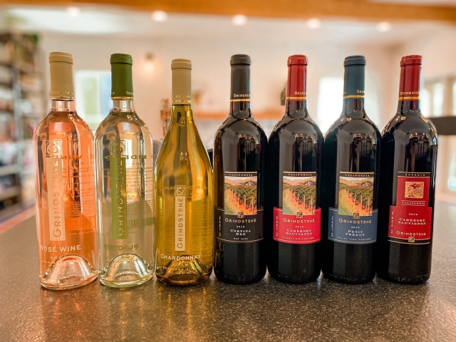 Seven wine bottles (rosé, white, red) lined on a bar counter, blurred background