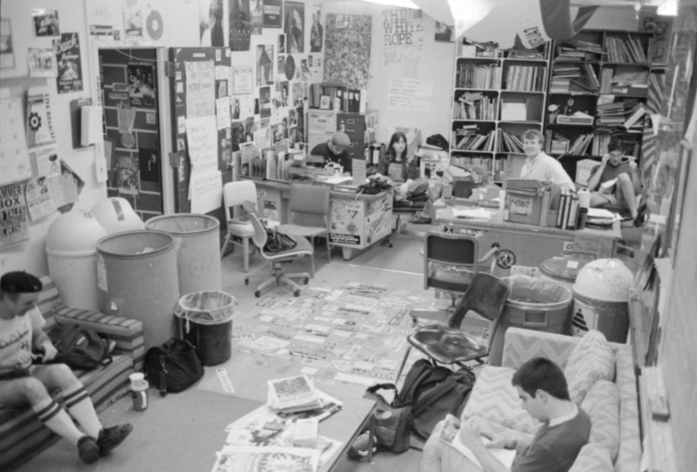 Archival photo showing students sitting on couches and behind desks in the cluttered side UC Davis radio station