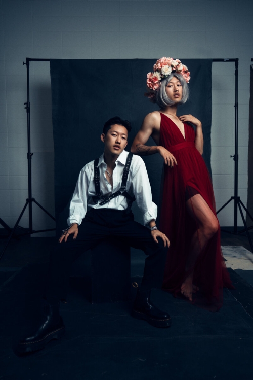 Photo shopped image of David Suh wearing a red dress and flower crown, posing next to himself wearing a white shirt and black slacks.