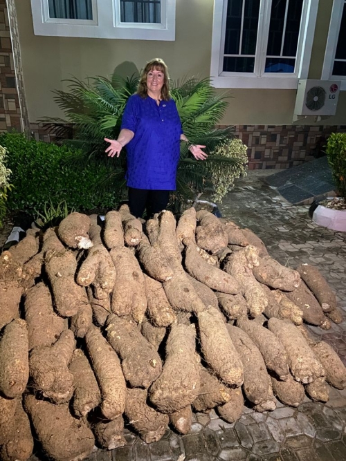 U.S. Ambassador Kathleen FitzGibbon poses with a pile of recently harvested yams.
