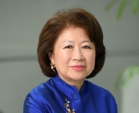 Middle-aged female with medium length hair in a bob hairstyle wearing a blue button down shirt with a vintage decorative detail.