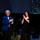 Sue Ebeler being presented with the Women & Philanthropy Impact Award on stage by Kelli Brown.