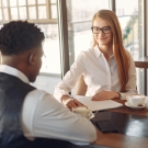image of a women interviewing a man, he is dressed in business professional attire