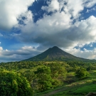 Lush green landscape with volcano and clouds