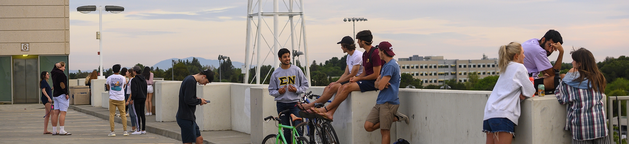 Various students on the top floor of the Hutchinson parking garage talking and watching the sun set.
